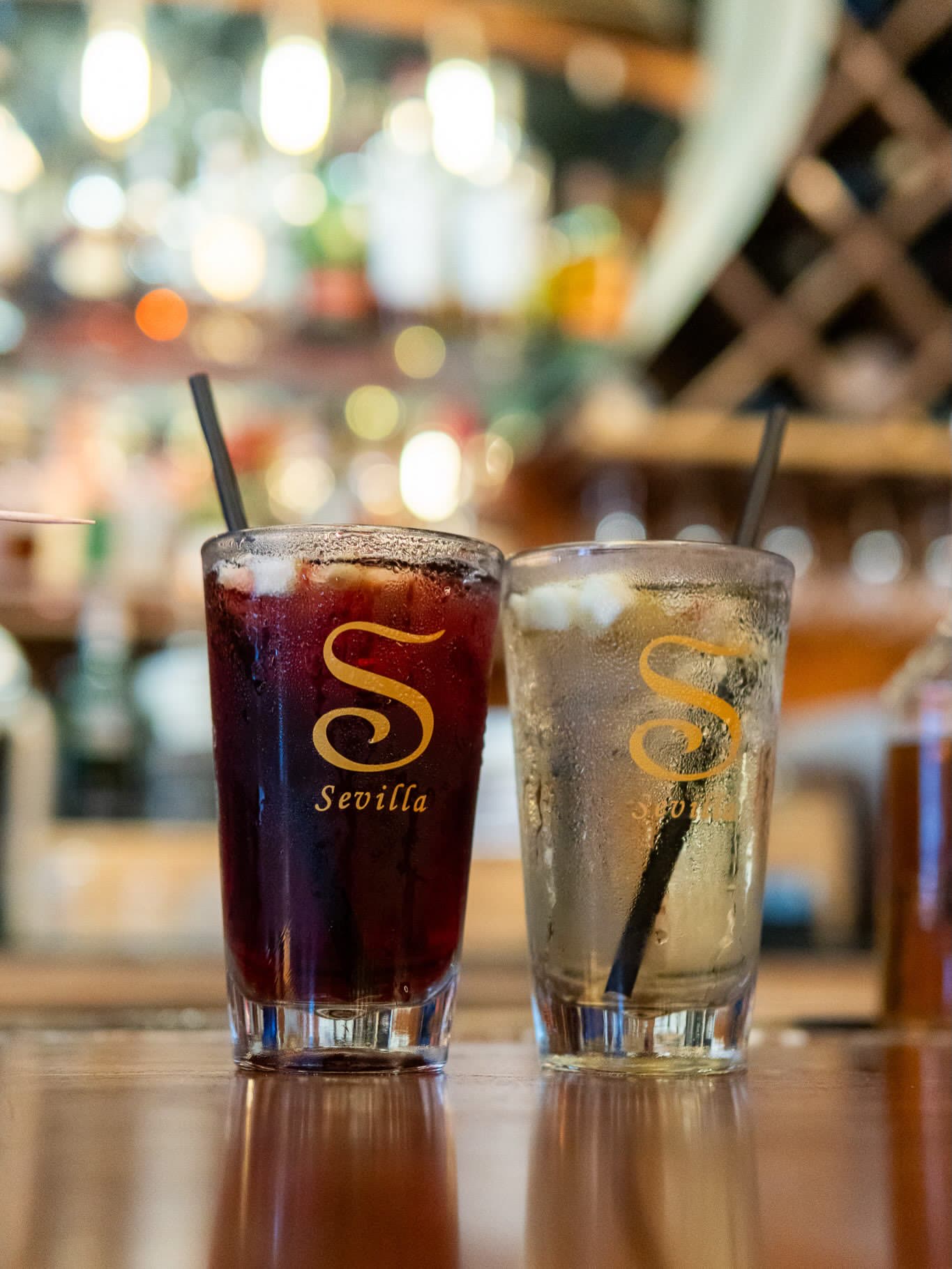 Sangria and a spritz, side by side in branded Sevilla glasses.