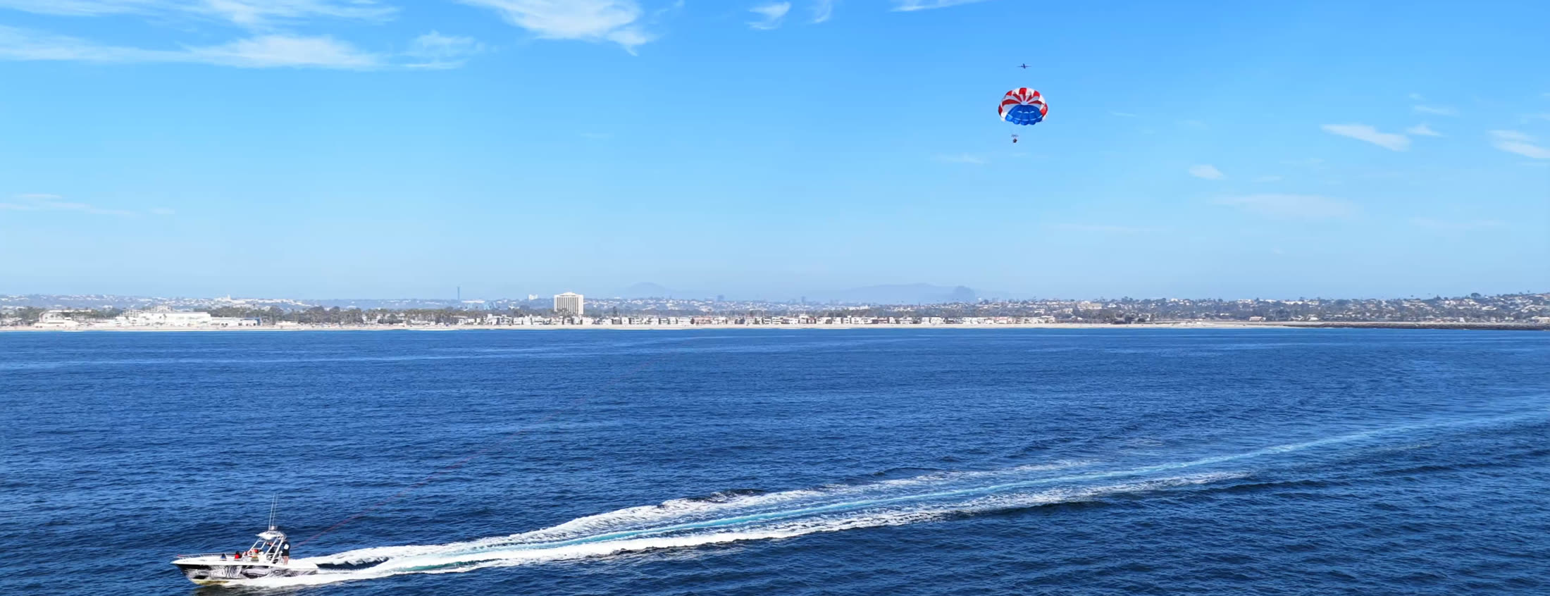 Drone view of the Mission Beach and Pacific Beach coastline with a parasail boat offshore