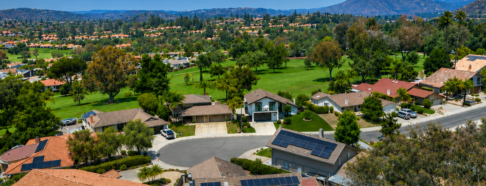 Aerial over the Rancho Bernardo neighborhood Jon Shea lists in, tile-roof homes and golf greens below the hills