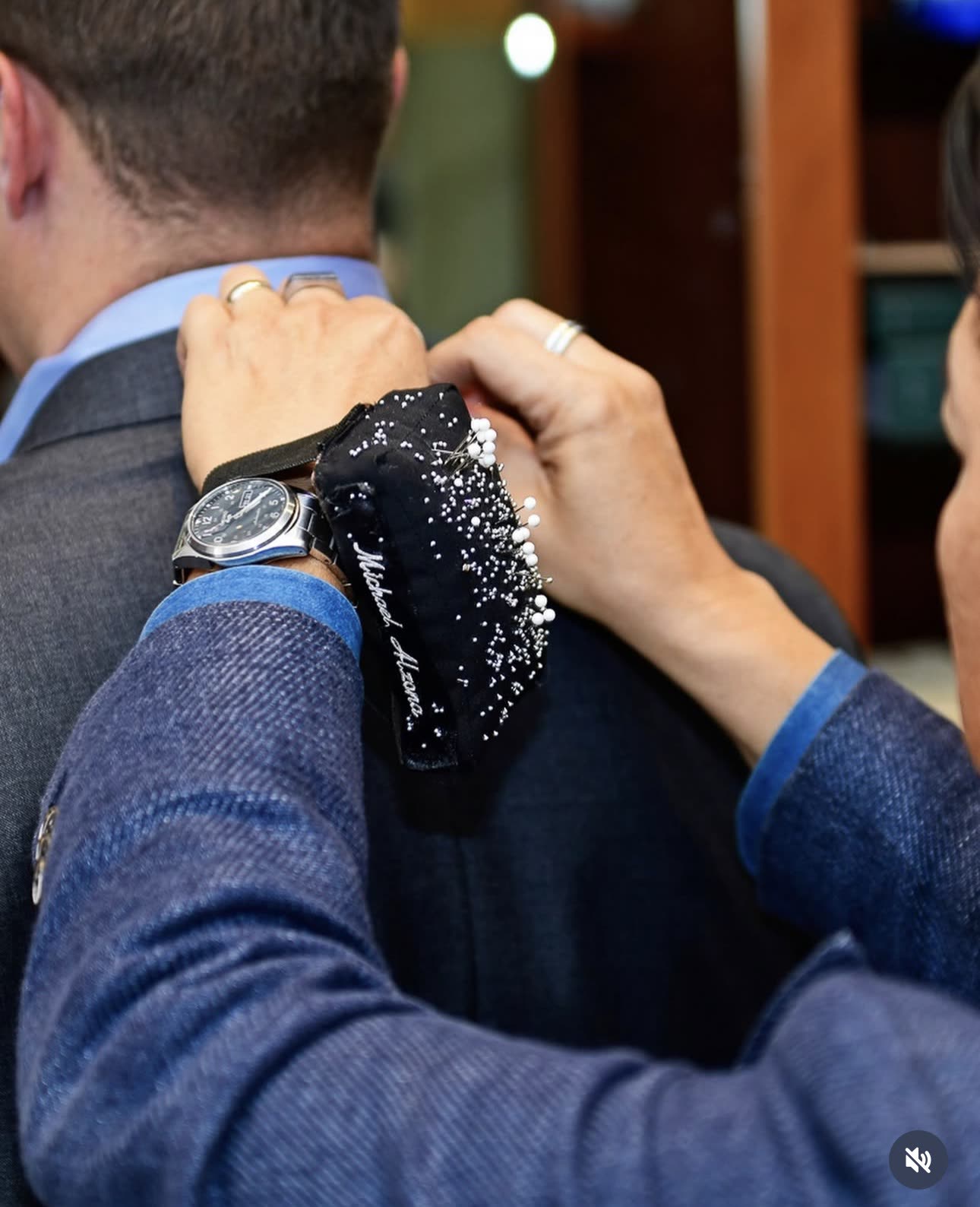 Close-up of a tailor pinning a jacket shoulder for a custom fitting.