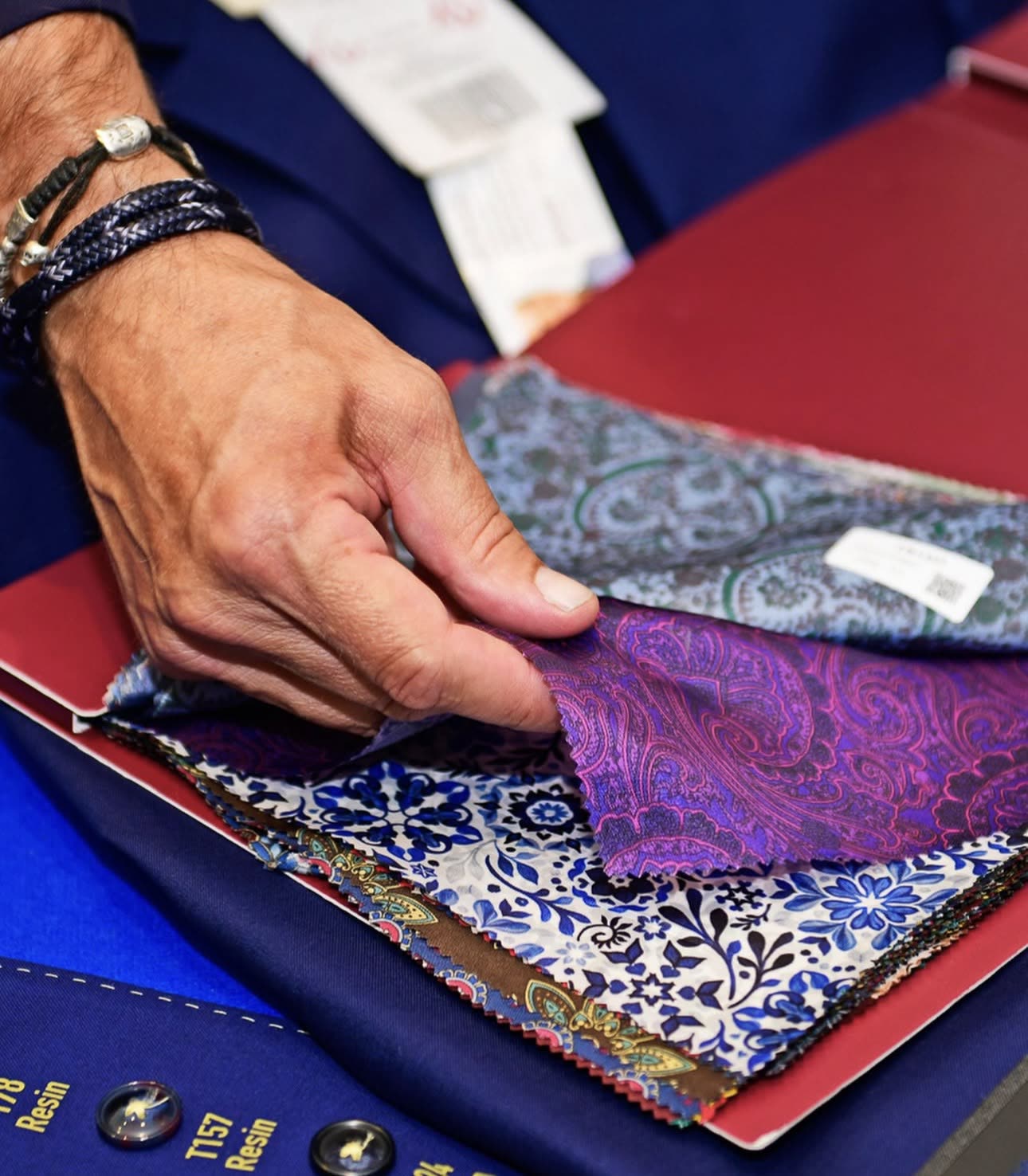 Sorting through paisley and floral fabric swatches for a custom shirt.